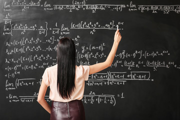 Female teacher writing on blackboard in classroom