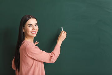 Female teacher writing on blackboard in classroom
