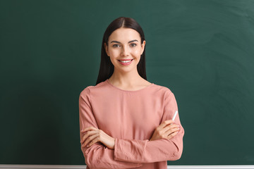 Female teacher near blackboard in classroom