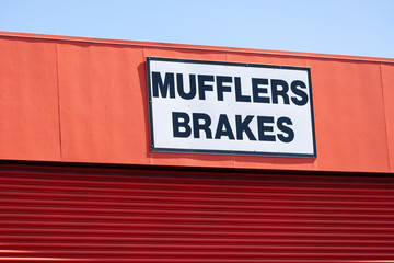 View of mufflers and brakes sign with black text on white background above garage door