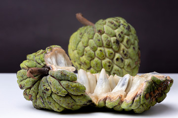 Fleshy teeth of Sugar-apple or 'Fruta de Conde' [Earl Fruit] as it is known in Brazil in the foreground with an intact specimen in the background against a dark background