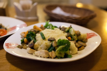 Couscous with chicken, fresh vegetables served with juice in restaurant. Dish with carrots, broccoli, mushrooms