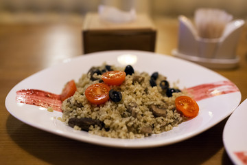 Bulgur with beef, cherry tomatoes and olives. Dish served in restaurant. Healthy eating
