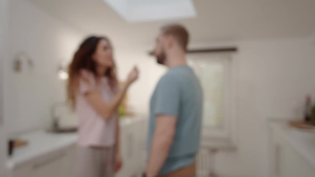 Thigh-up shot with blurred effect of anonymous man and woman having emotional argument in kitchen at home, gesticulating, shouting, blaming, reproaching, then pushing and slapping each other