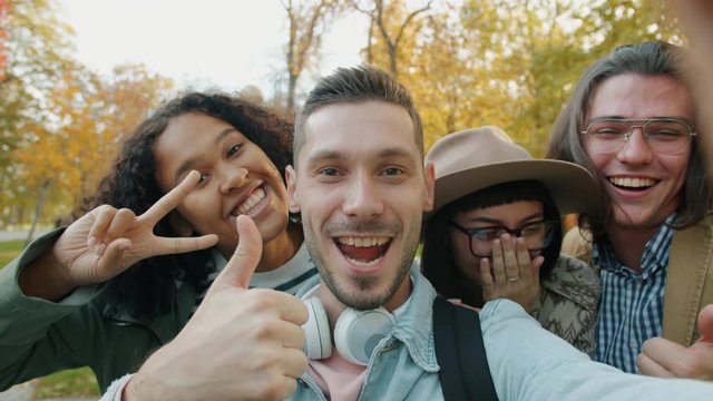 Portrait of cheerful young students girls and guys taking selfie in forest posing looking at camera together. Modern youth and emotions concept.