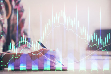 A woman hands writing information about stock market in notepad. Forex chart holograms in front. Concept of research. Double exposure