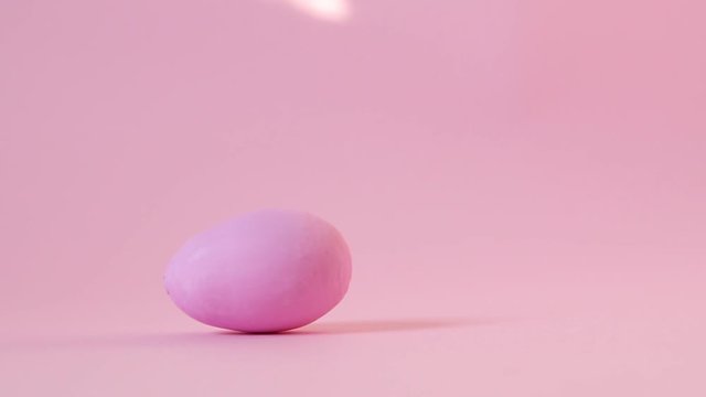 Happy easter concept.Egg spinning. Wooden egg decorated with gold and pink paint revolve on pink background
