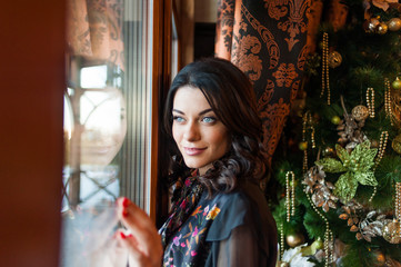 Beautiful woman in evening dress near Christmas tree