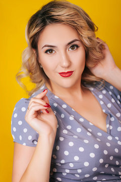 Girl with red lips and a dress in peas on a yellow background. Pin-up Portraits