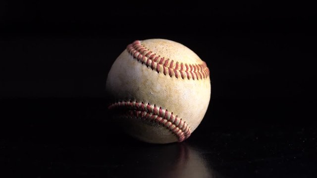 A baseball spinning on a black background. 4K