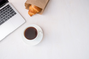 Cup of coffee from a laptop computer with fresh croissants. on white background.concept of education