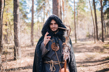 A man with a beard and a mustache in a robe and coat with a staff in his hand. A magician, a shaman...