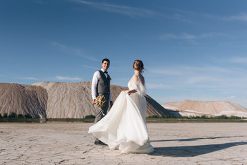 Fototapeta na wymiar Beautiful elegant couple of newlyweds in love on a beautiful natural background of salt mountains and quarries