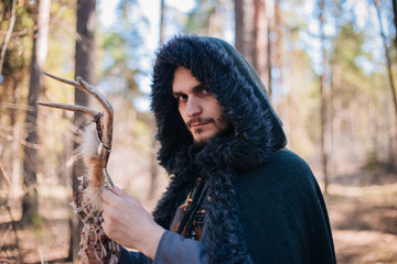 A man with a beard and a mustache in a robe and coat with a staff in his hand. A magician, a shaman...