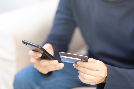 Man wear blue T-shirt Hands with smartphone and credit card.