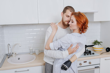 Tired husband and wife hugging in the kitchen.