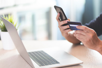 Man wear blue T-shirt Hands with smartphone and credit card laptop on desk space for text composition