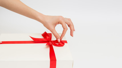 Female hands holding a gift box white with a red ribbon