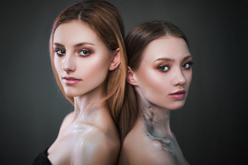 Studio portrait of a model. Body art gray roses. Beautiful two girls on a gray background.