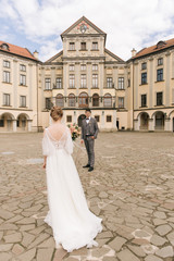 Beautiful elegant couple of newlyweds in love on the background of an old building and paving stones, European wedding