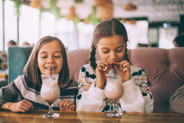 Children drink smoothie in family cafe