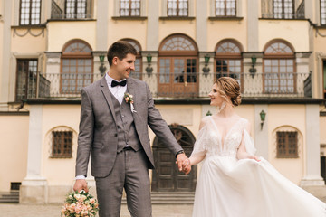 Beautiful elegant couple of newlyweds in love on the background of an old building and paving stones, European wedding