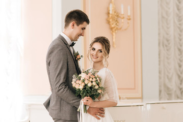 Beautiful elegant couple of newlyweds in love in a luxurious interior near the piano