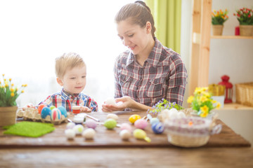 Mother and her son painting Easter eggs. Happy family preparing for Easter day