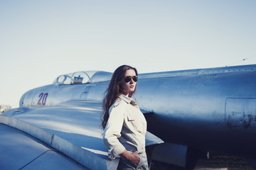 portrait of a beautiful military woman pilot in sunglasses near the plane