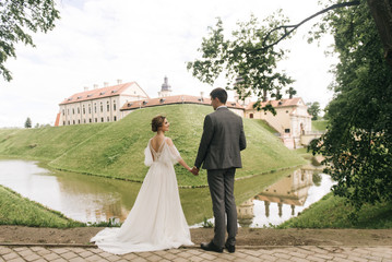 Beautiful elegant couple of newlyweds in love on the background of an old castle, European wedding