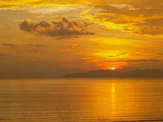 view seaside evening of golden sea with yellow sun light and cloudy sky background, sunset at Pak Meng Beach, Trang Province, southern of Thailand.