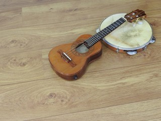 Close-up of two Brazilian musical instruments: cavaquinho and pandeiro (tambourine) on a wooden surface. They are widely used to accompany samba and choro, two popular Brazilian rhythms. Top view.