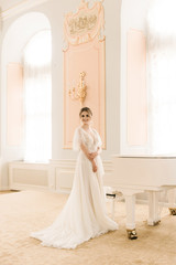 Obraz premium Portrait of a beautiful bride next to a piano in a luxurious interior