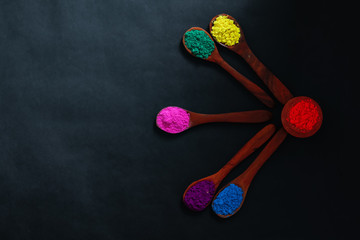 Fototapeta na wymiar Indian Festival Holi , Colors in wooden spoon on dark background 