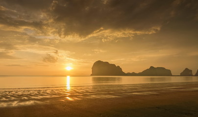Fototapeta premium view seaside panorama evening of mountains on the beach with reflection on woater and yellow sun light with cloudy sky background, sunset with raining at Pak Meng Beach, Trang Province, Thailand.