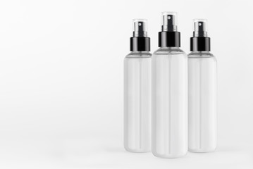 Three tall transparent spray dispenser bottles for cosmetics with liquid on white background, mock up for branding,  presentation, design.