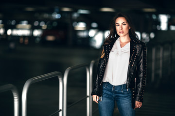 Beautiful fashion model in black leather jacket posing outdoor.