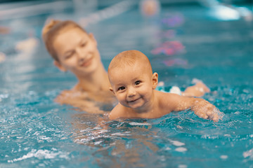 Mother and little son having fun in a swimming pool