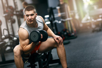 Fototapeta na wymiar Fit man in sportswear focused on exercise for biceps in the gym