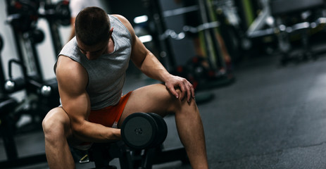 Obraz na płótnie Canvas Fit man in sportswear focused on exercise for biceps in the gym