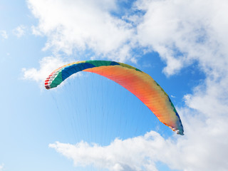 The dome of the paraglider with slings against the blue sky and clouds