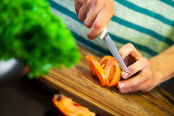 Girl cutting red tomato with knife