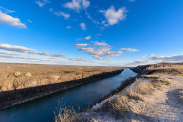 panorama of nature in early spring. river in the sun, cloudy blue sky at sunset