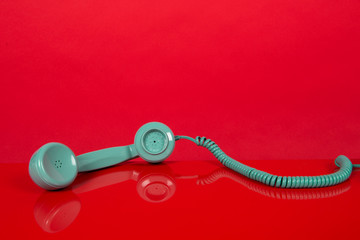 Vintage blue telephone receiver lying on a red background
