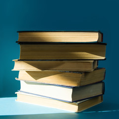 stack of old books, on a blue background on a Sunny day
