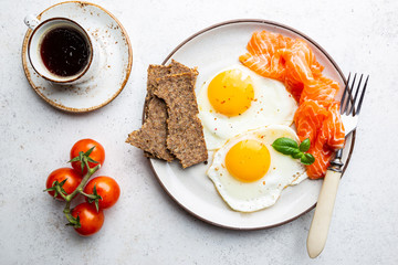 Top view of healthy breakfast with fried eggs and smoked salmon in a plate