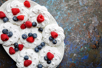 White meringues cakes with berries, raspberry and blueberry. Flat lay, top view