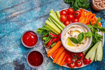 Hummus platter with assorted snacks. Hummus in bowl and vegetables sticks. Plate with Middle...