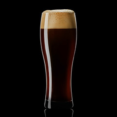 Weizen glass of black stout beer on a black background. Isolated studio shot with reflection.