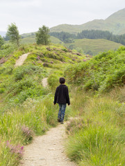 Rückansicht des Jungen zu Fuß auf Grassy Hill Pathway in Glenfinnan